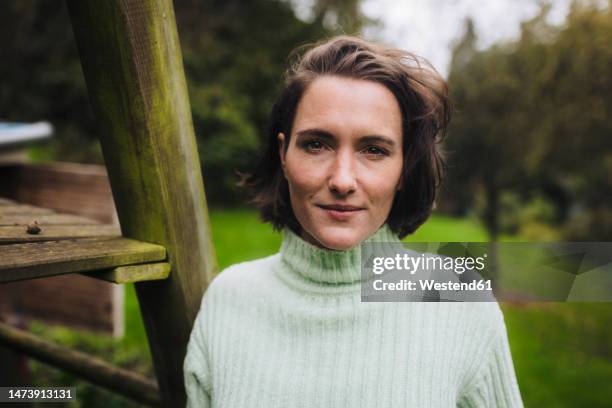 smiling woman standing in back yard - woman front and back stock-fotos und bilder