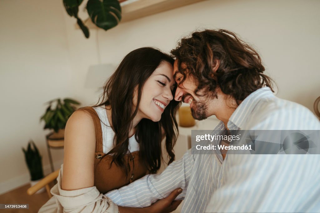 Happy couple touching foreheads at home