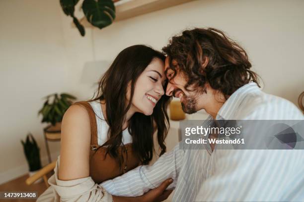 happy couple touching foreheads at home - paixão imagens e fotografias de stock