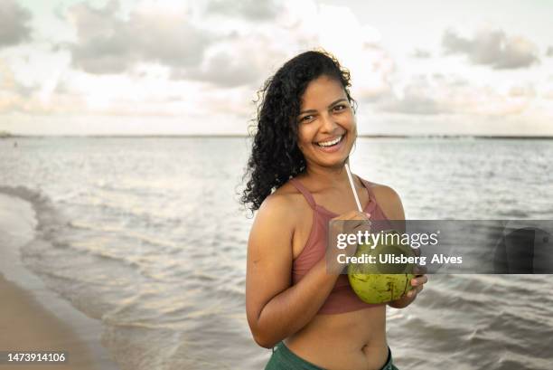 woman drinking coconut water on the beach - coconut water stock pictures, royalty-free photos & images