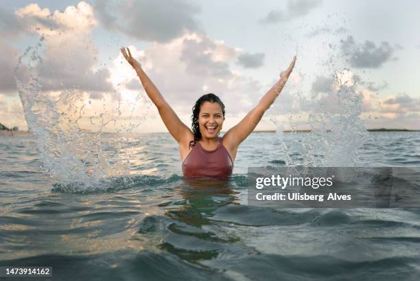 woman smiling taking a bath in the sea - bathing in sunset stockfoto's en -beelden