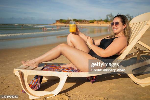 tourist drinking cocktail on tropical beach - woman plus size swimsuit stock pictures, royalty-free photos & images