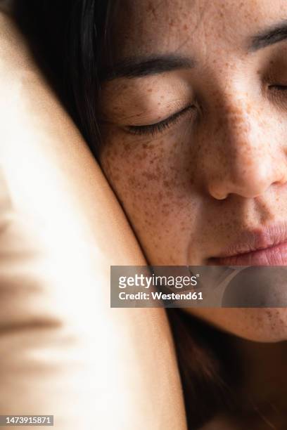 woman with eyes closed resting on pillow - silk pillow stock-fotos und bilder
