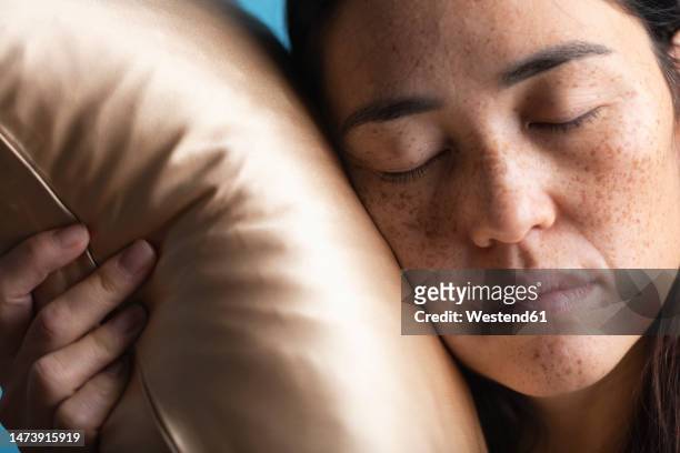 woman with eyes closed sleeping on silk pillow - silk pillow stock-fotos und bilder