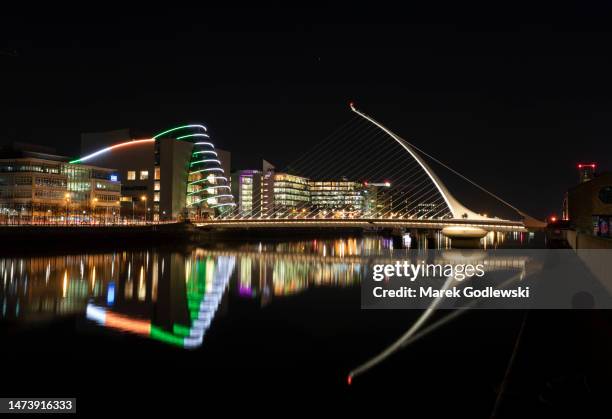 samuel beckett bridge and dublin convention center illumination in national colors,  reflecting in water, dublin, ireland - docklands stock pictures, royalty-free photos & images