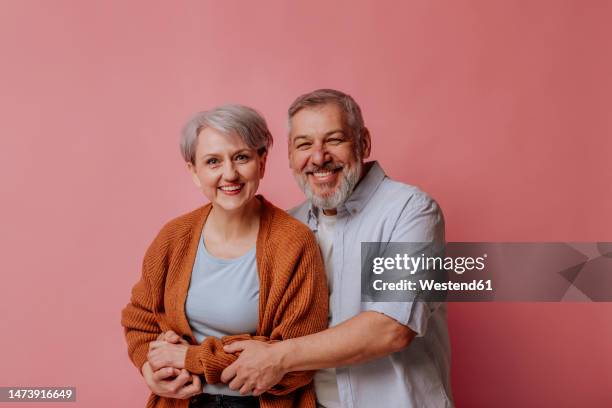 mature man and woman against pink background - happy man pink background stock pictures, royalty-free photos & images