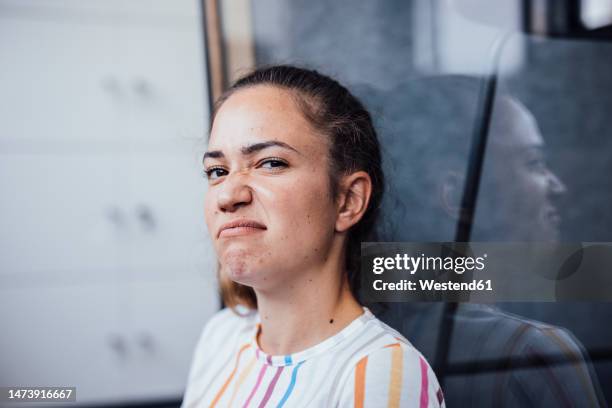 businesswoman making face sitting in office - facial expression stock-fotos und bilder