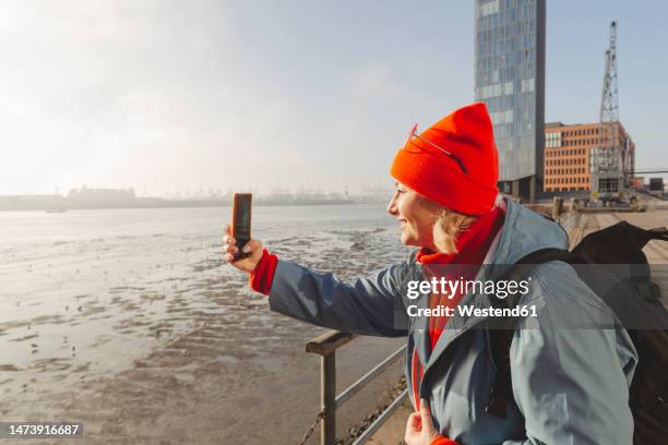 woman photographing river through smart phone - die letzte reise photo call in hamburg stock-fotos und bilder