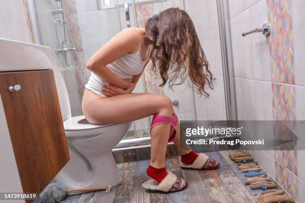 woman with stomach pain on toilet - people peeing stockfoto's en -beelden