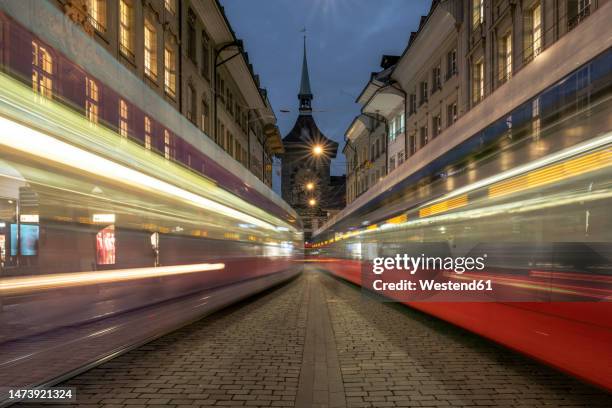 switzerland, bern canton, bern,blurred motion of cable cars passing street at dusk - berne canton fotografías e imágenes de stock