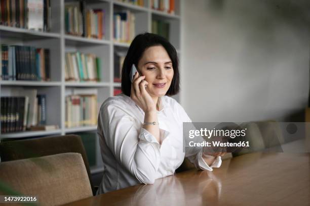 happy businesswoman talking on mobile phone at workplace - white blouse stock-fotos und bilder