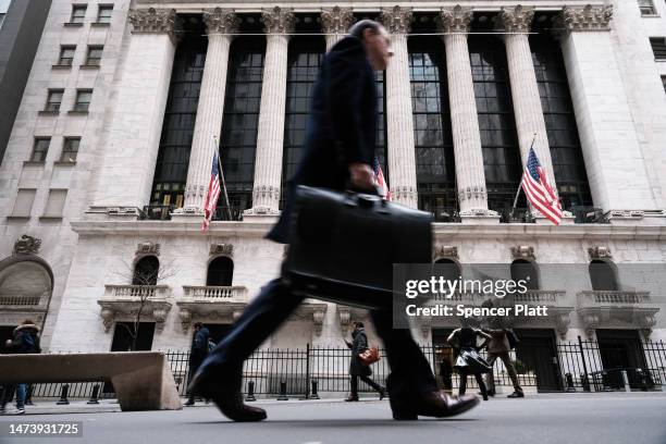 People walk past the New York Stock Exchange on March 16, 2023 in New York City. Stocks fell again in morning trading as investors continue to show...