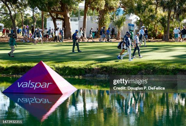 Valspar signage is seen as Justin Thomas of the United States walk the 16th fairway during the first round of the Valspar Championship at Innisbrook...