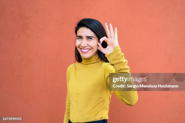 latino woman looking at the camera and giving the ok sign - okサイン　女性 ストックフォトと画像