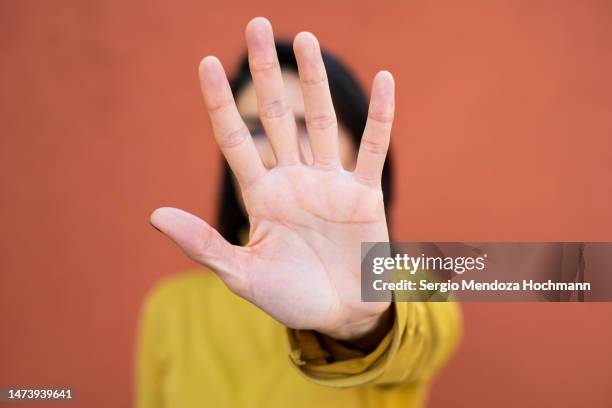 latino woman looking at the camera and gesturing to stop, close up, face obscured by hand - vorurteil stock-fotos und bilder