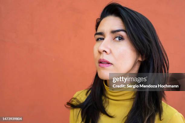 latino woman raising an eyebrow and looking at the camera, medium shot - argwohn stock-fotos und bilder