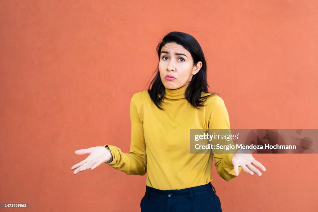 Latino woman shrugging with her hands to the sides