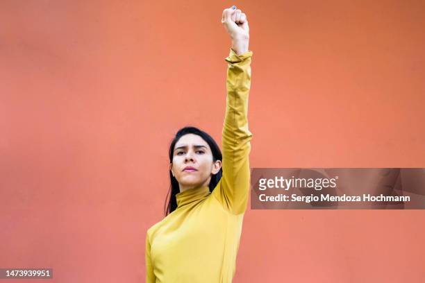 latino woman raising her clenched fist for women empowerment, female empowerment, liberation - geballte faust stock-fotos und bilder