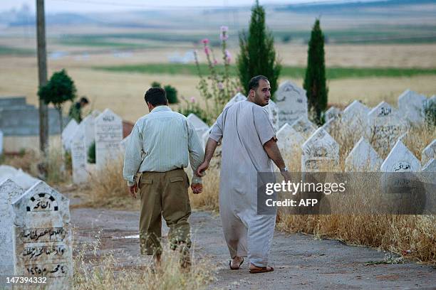 Syrians men walk through a cemetery in Tal Refaat village near Aleppo during the burial of 70-year-old Amina Ahmed Kabso, who was killed in the...