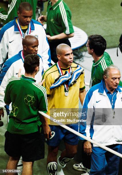 Brazil striker Ronaldo leaves the field dejectedly with his Nike match boots around his neck after the 1998 FIFA World Cup Final between France and...