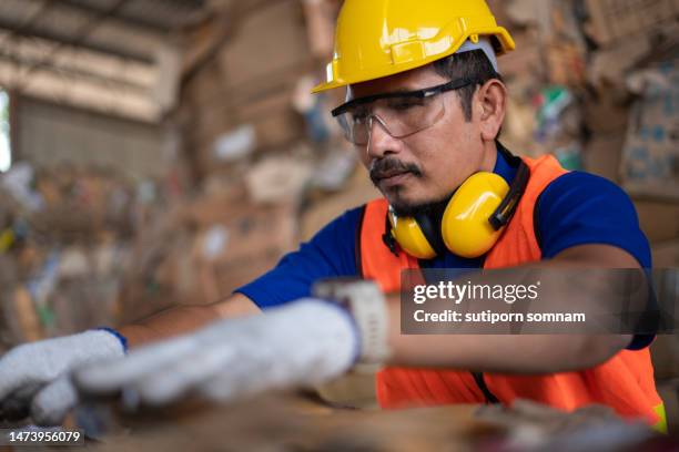garbage factory workers sorting bales of recyclable waste. - ornement auriculaire photos et images de collection