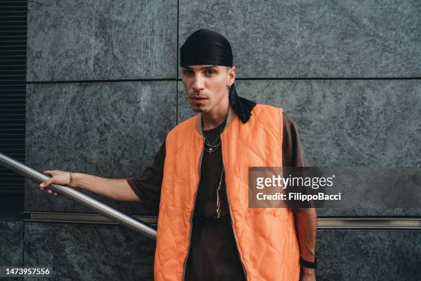 portrait of a young adult man wearing cool urban clothes in the city - orange bandana stock pictures, royalty-free photos & images