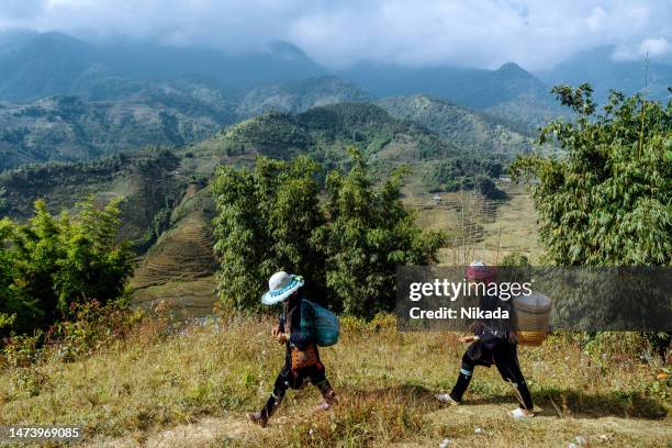 dos mujeres de la tribu black hmong haciendo senderismo en las montañas cerca de sapa, vietnam del norte - sa pa fotografías e imágenes de stock