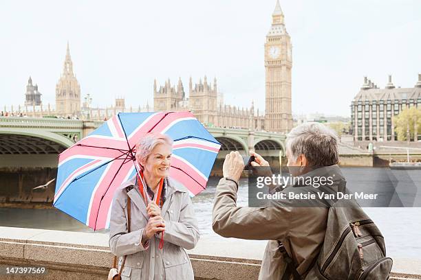 senior man photographs woman in front of big ben. - old uk flag stockfoto's en -beelden