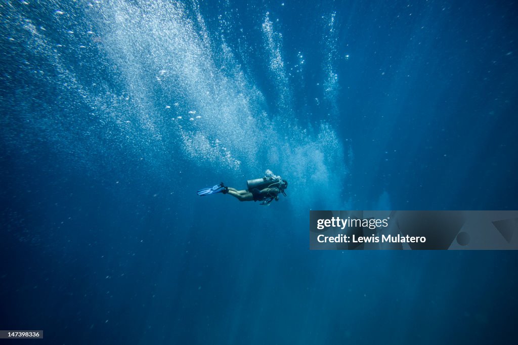 Scuba diver in deep open ocean with oxygen bubbles