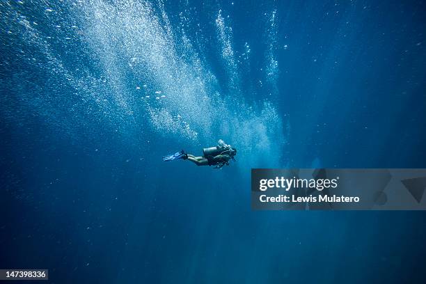 scuba diver in deep open ocean with oxygen bubbles - diver imagens e fotografias de stock