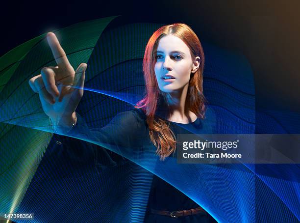woman interacting with futuristic light trails - touching stock pictures, royalty-free photos & images