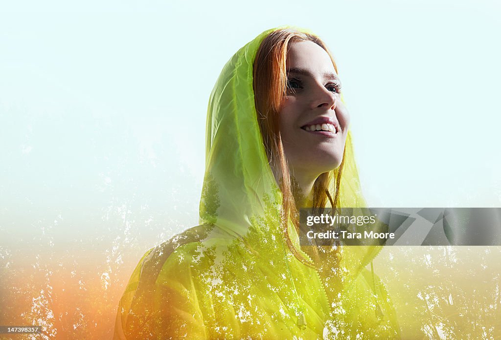 Woman in hooded top smiling with trees
