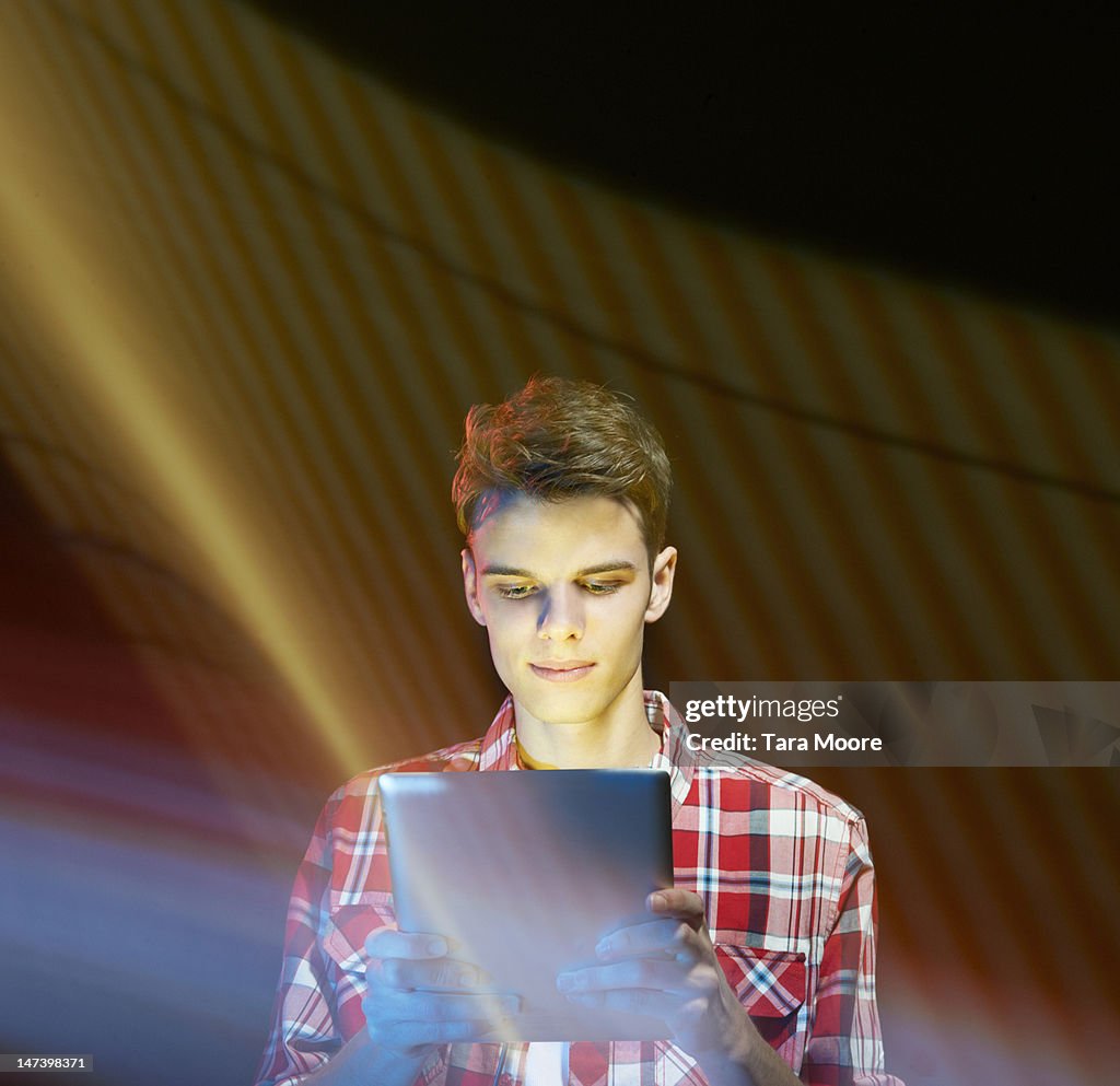 Young man looking at digital tablet with light