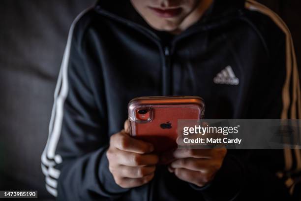 Year-old boy looks at a smartphone screen on March 16, 2023 in Bath, England. Following the lead of the EU Commission and several US administrations,...
