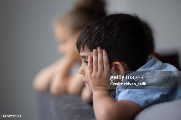 kleine kinder, die den regen durch das fenster beobachten - autismus stock-fotos und bilder