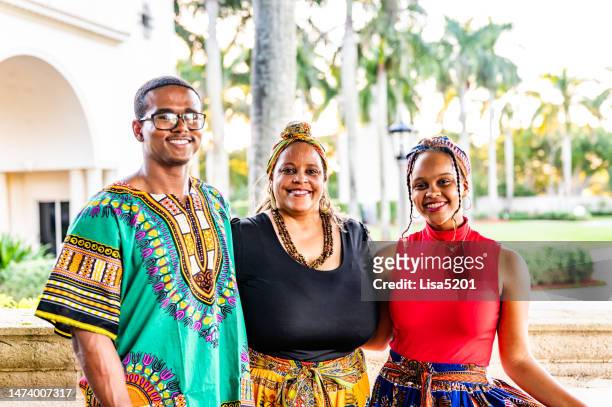 mother and adult son and daughter dressed in dashiki and traditional clothing to celebrate kwanzaa in outdoor happy family portrait - kwanzaa celebration stock pictures, royalty-free photos & images