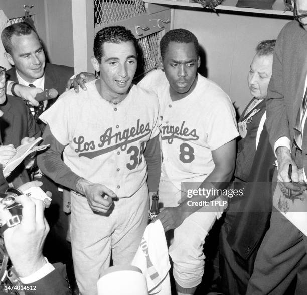 Pitcher Sandy Koufax and catcher John Roseboro of the Los Angeles Dodgers are surrounded by reporters in the locker room after Koufax set a new World...