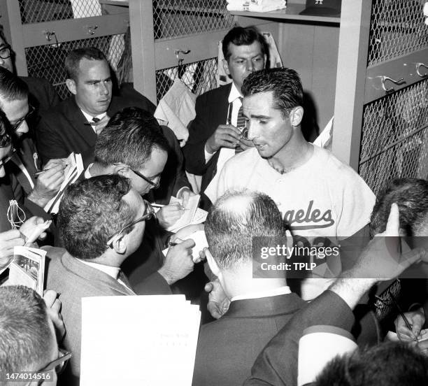 Pitcher Sandy Koufax of the Los Angeles Dodgers is interviewed by reporters in the locker room after Koufax set a new World Series record during Game...