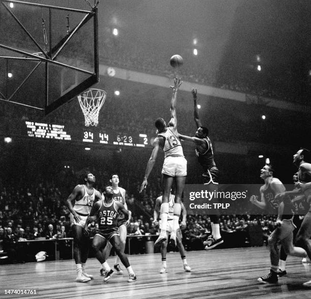 Bill Russell of the Boston Celtics takes the hook shot over Wilt Chamberlain of the Philadelphia Warriors as Woody Sauldsberry of the Warriors along...