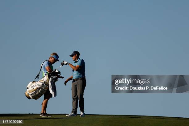 Adam Schenk of the United States pulls a club from his bag alongside caddie David Cooke before hitting an approach on the fifth fairway during the...