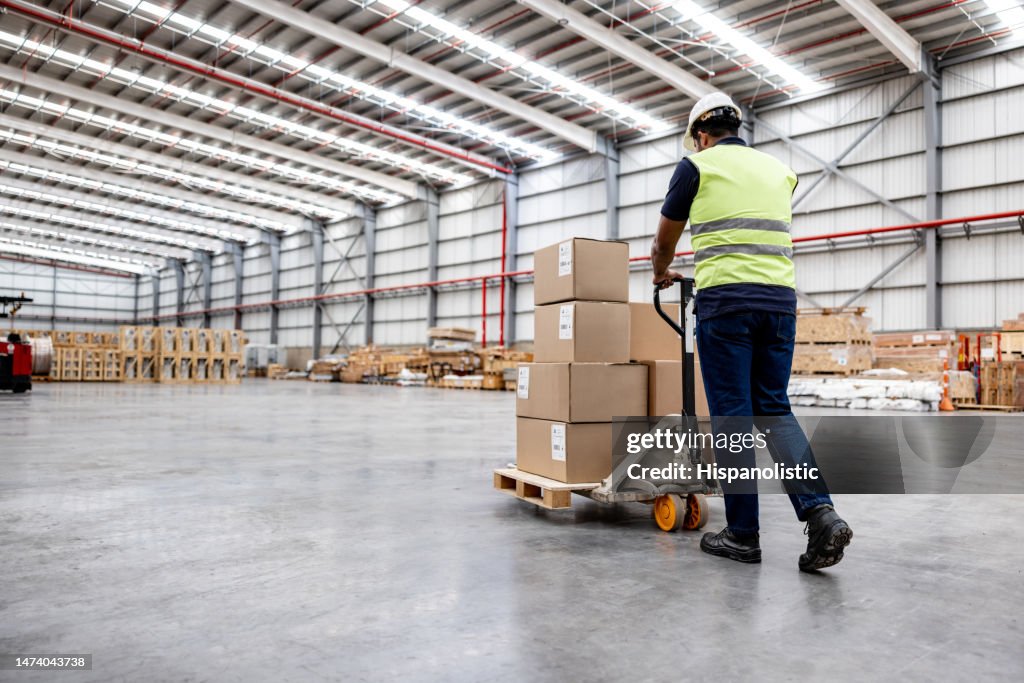 Man working at a distribution warehouse and moving boxes using a forklift