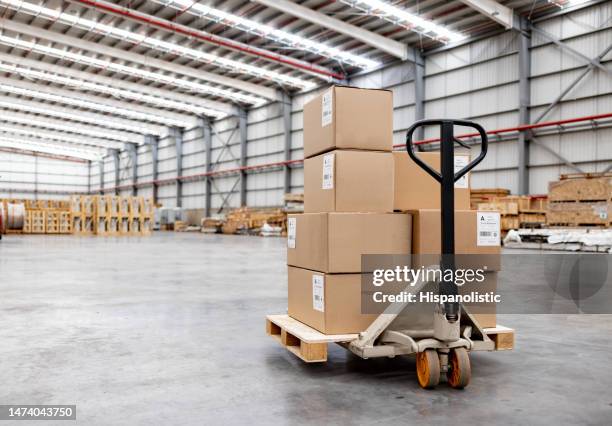 pallet jack moving boxes at a distribution warehouse - flat bed dolly stock pictures, royalty-free photos & images