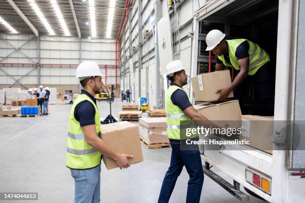 workers at a distribution warehouse loading boxes on a truck - unloading stockfoto's en -beelden