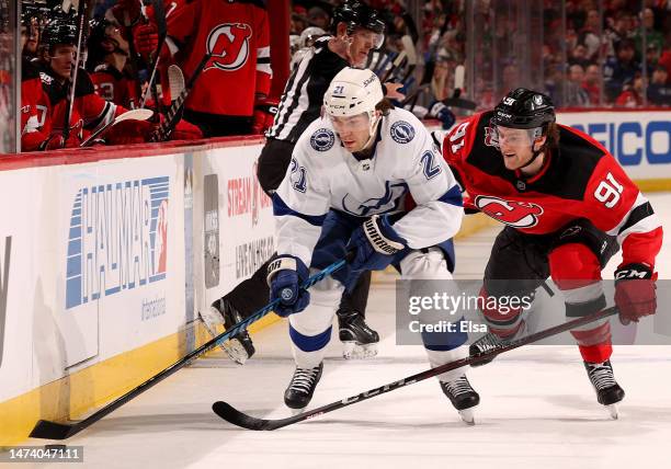 Brayden Point of the Tampa Bay Lightning and Dawson Mercer of the New Jersey Devils fight for the puck in the third period at Prudential Center on...