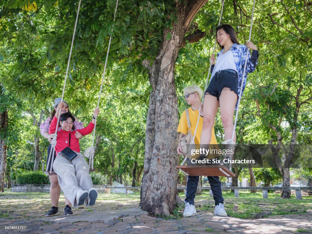 Grupo de jóvenes asiáticos divirtiéndose y disfrutando jugando en el columpio en el parque