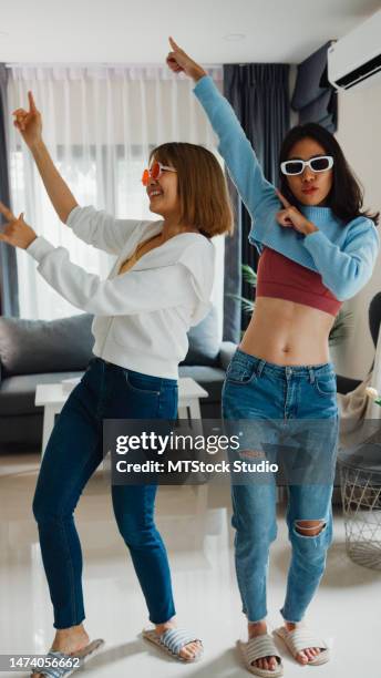 young asian lesbian couples influencer having fun dancing trendy music together live online screen ig reel tiktok in living room at home. dancing and singing in a cozy room. vertical screen. - dance challenge stock pictures, royalty-free photos & images