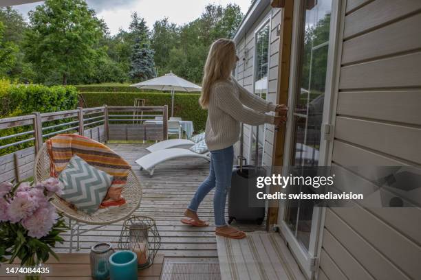 young woman entering her cabin vacation rental - french garden stock pictures, royalty-free photos & images