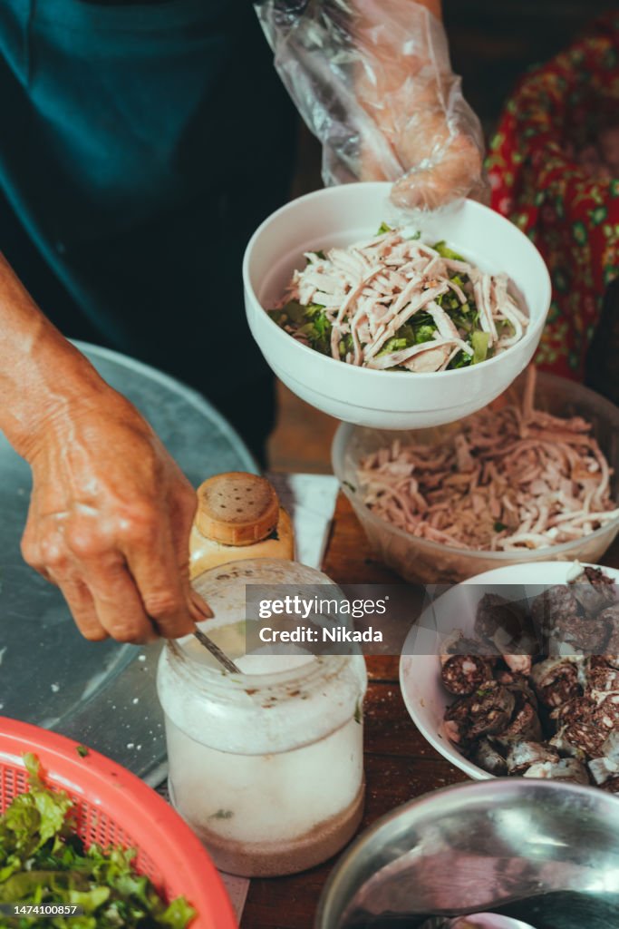 Senior woman preparing Pho soup at market in Bac ha, Vietnam
