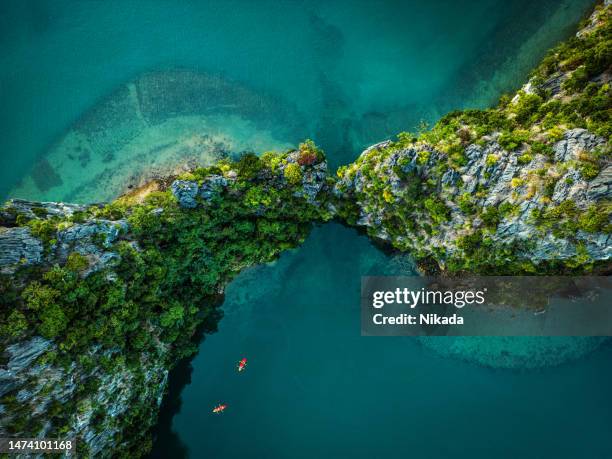 ベトナムのハロン湾のターコイズブルーの水に浮かぶ岩やカヌーのドローンビュー - ハロン湾 ストックフォトと画像