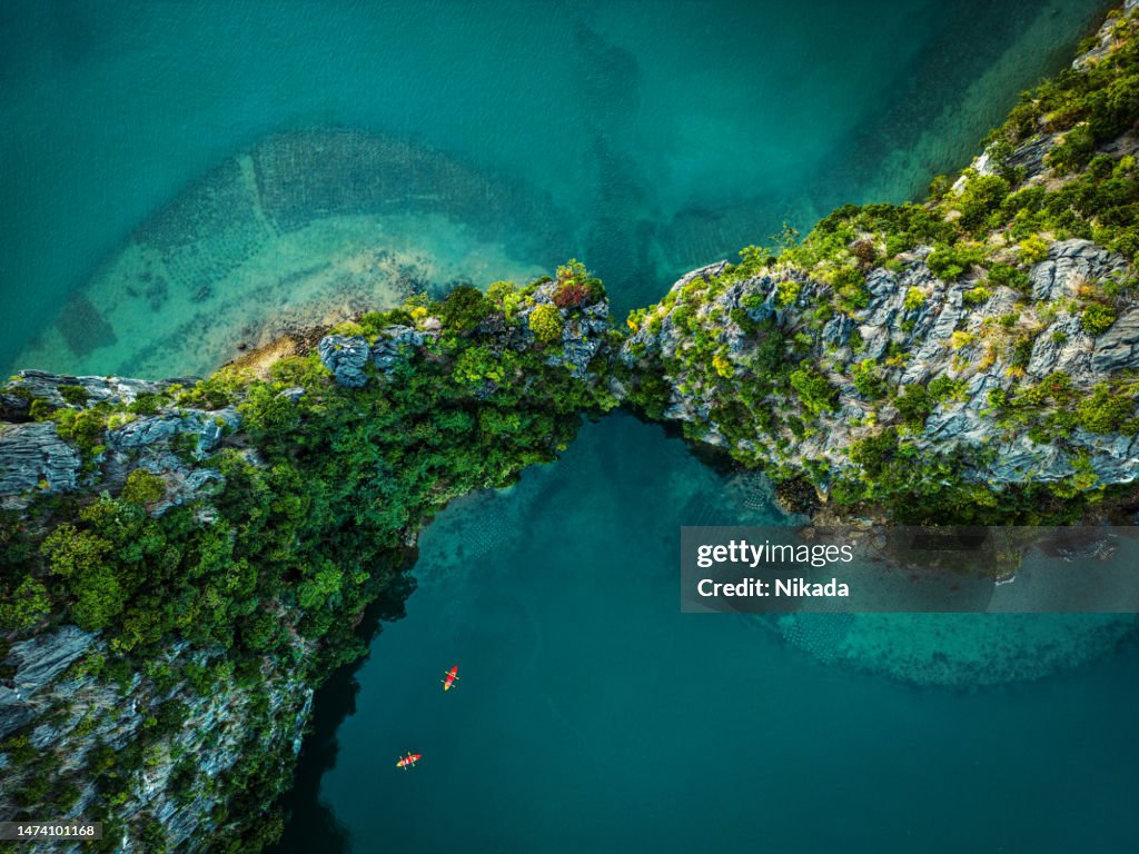 Drone view on rocks and canoes floating on turquoise water in the Halong Bay, Vietnam